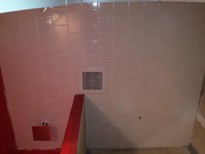 Het getegelde plafond van onder gezien, met de rainshower linksonder